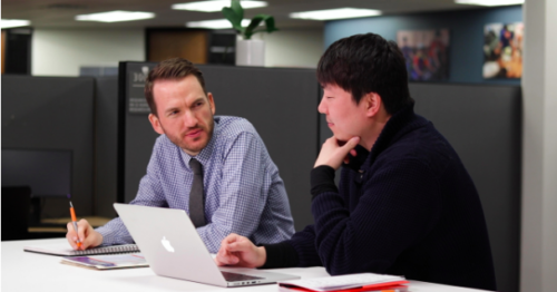 Two men discuss research at a table