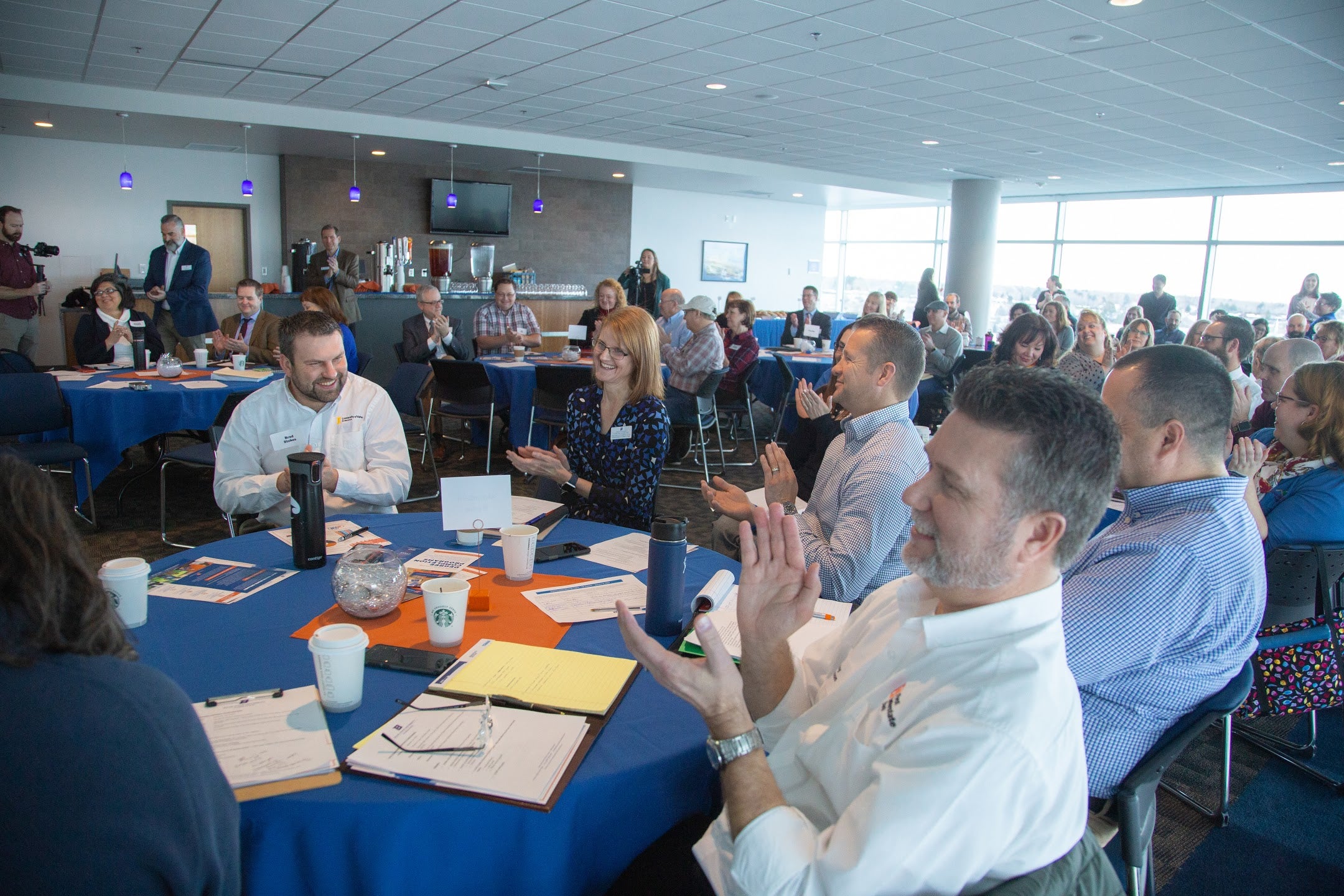 Crowd of summit attendees applauding.