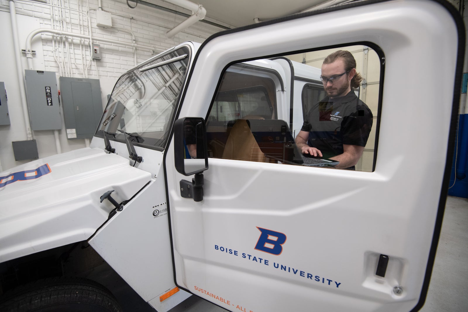 Man performing computer diagnostics on an electric vehicle