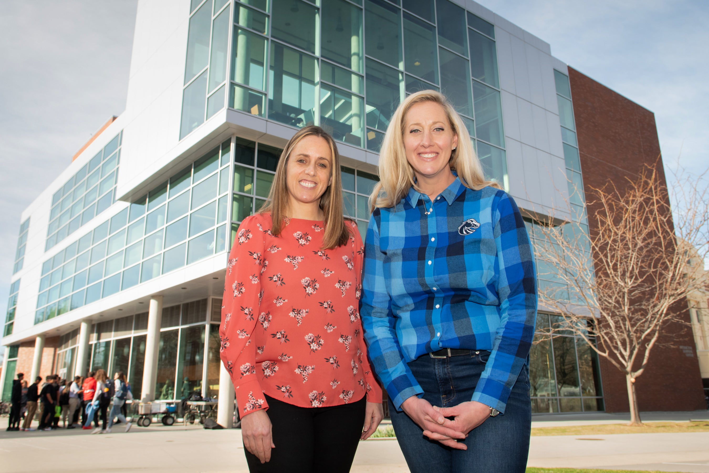 Aida Midgett and Katy Weiser stand side by side in front of building