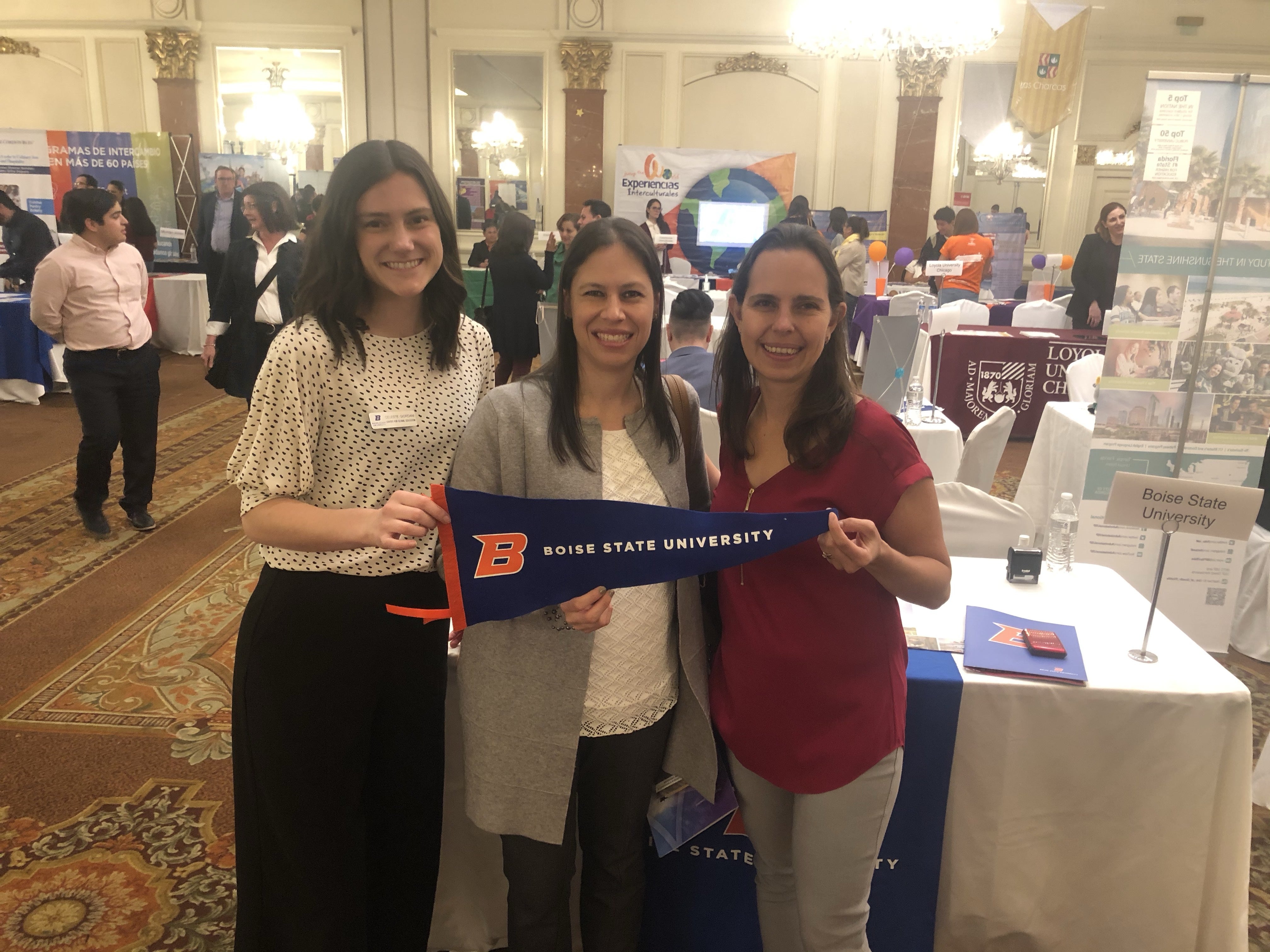 Three women standing side by side holding Boise State banner