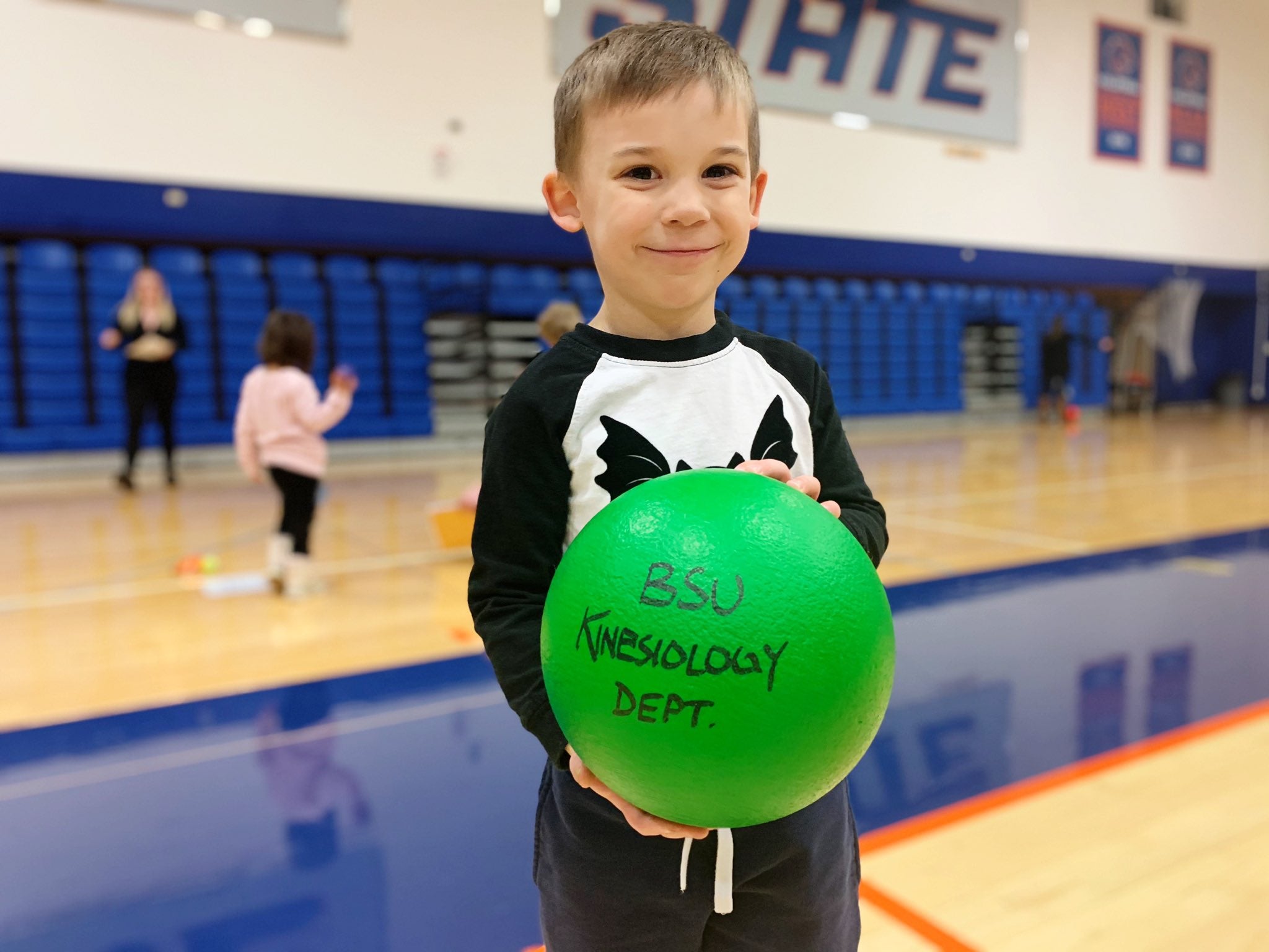 Child in Bronco Gym holds rubber ball that says Boise State Kinesiology Department