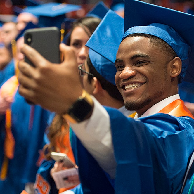 Student taking a selfie with cell phone during commencement ceremony