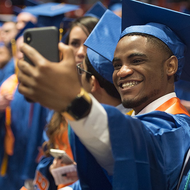 Student taking a selfie with cell phone during commencement ceremony