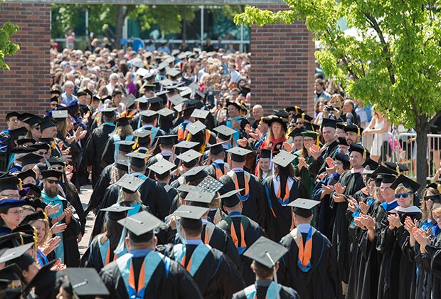 Graduates walking past faculty