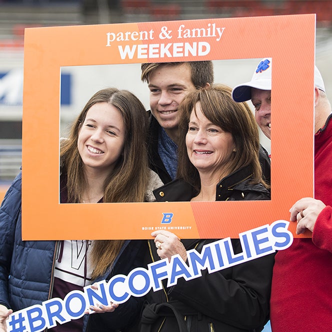 Student with family posing on blue turf