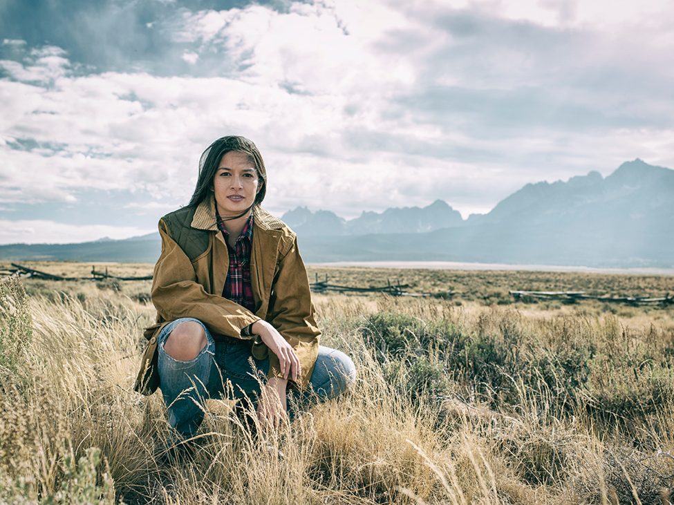 The author crouches in a field on a sunny day.