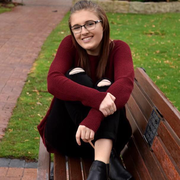 The author sits, smiling, on a park bench.