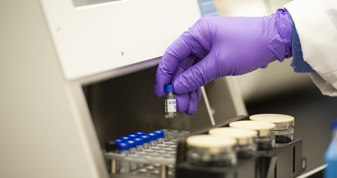 A lab worker wearing gloves and handling a sample