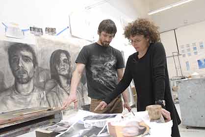 student and professor standing over drawings