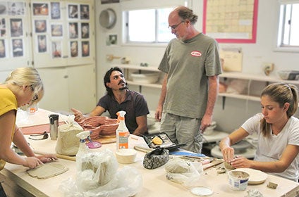 professor talking to students working with clay