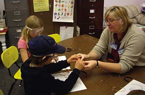 student helping kids make wire ants