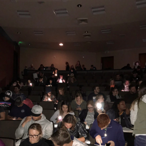 Students in classroom using phone flashlights