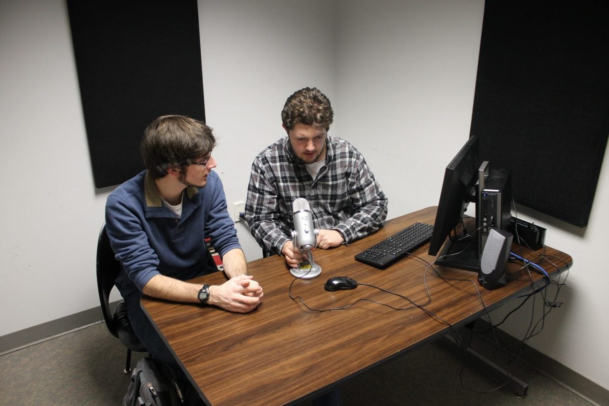 Two students creating podcast with library equipment