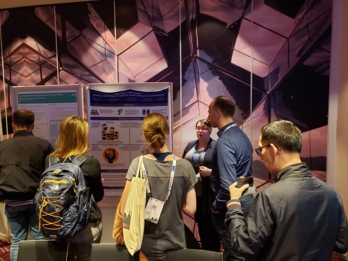 Photo of Ashlee presenting her research poster to several students at the RecSys conference