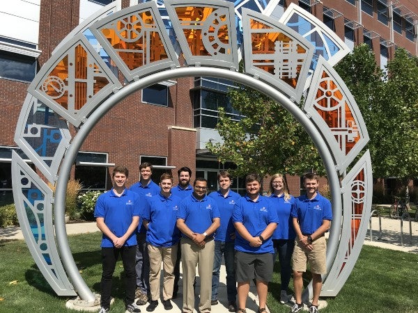 members of the Industrial Assessment Center pose by a sculpture