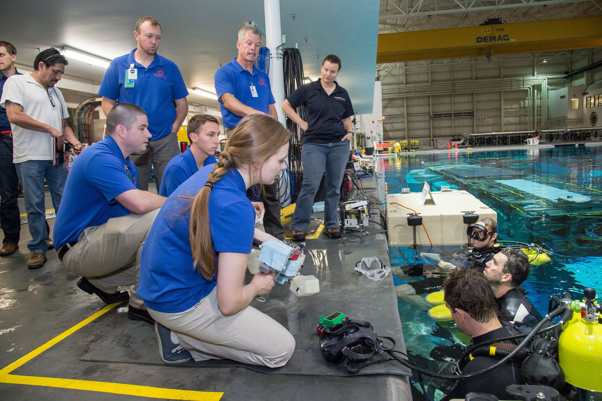 Students speak with divers in a pool