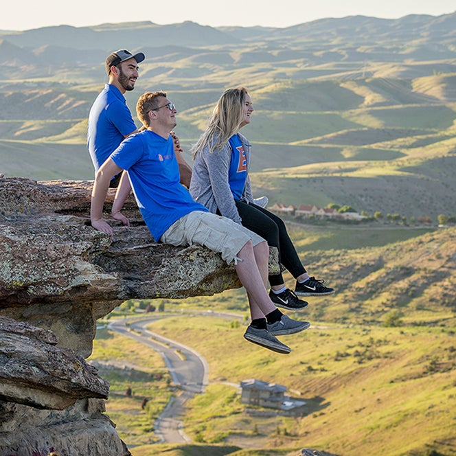 Three students sitting on a ledge