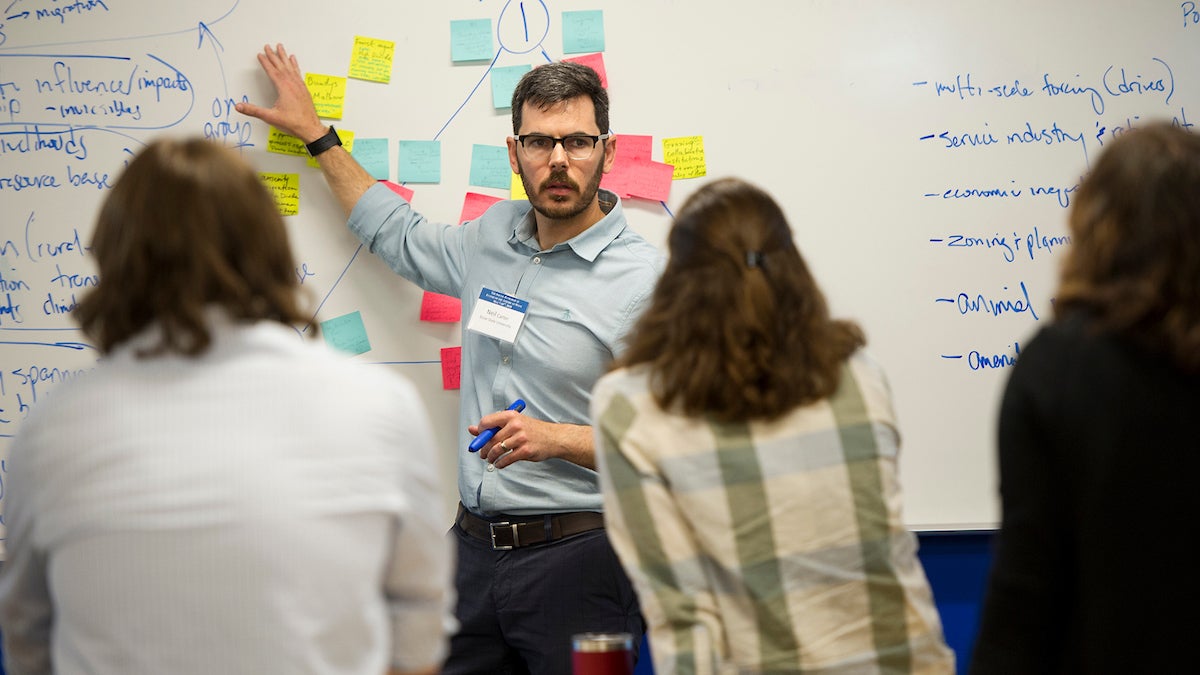 A Boise State faculty member pointing to a white board while talking to three students