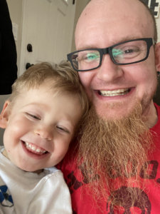 Chris Saunders and his son sitting on the couch